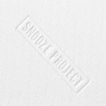 Nahaufnahme einer weißen, strukturierten Oberfläche mit kleinen Perforationen und dem Schriftzug SNOOZE PROJECT, der diagonal in der Mitte eingeprägt ist.